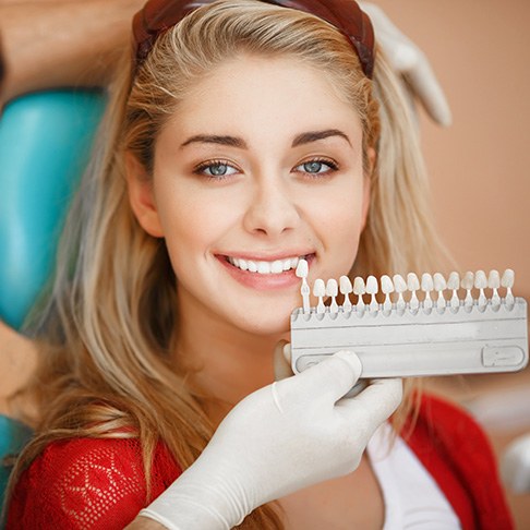 A dentist assessing the shade of a woman’s smile